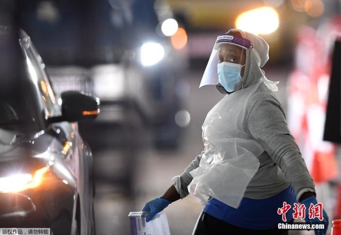 當(dāng)?shù)貢r(shí)間12月18日，英國(guó)政府公布的數(shù)據(jù)顯示，當(dāng)天英國(guó)新增奧密克戎毒株感染病例10059例。鑒于奧密克戎毒株感染病例激增，住院人數(shù)不斷上升，倫敦市長(zhǎng)宣布倫敦進(jìn)入“重大事故”狀態(tài)。圖為倫敦的一個(gè)免下車檢測(cè)中心，一名醫(yī)務(wù)工作者正準(zhǔn)備對(duì)司機(jī)進(jìn)行核酸檢測(cè)。