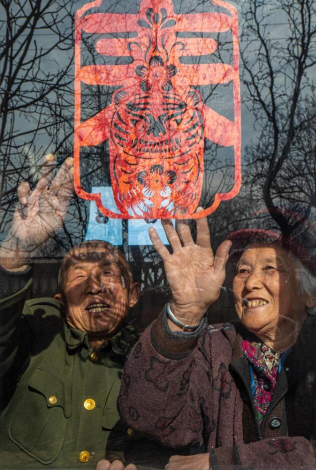 臘月里，霍州市師莊鄉(xiāng)馮南垣村村民師榮光(左)在災(zāi)后重建的新家里貼窗花。(霍州市委宣傳部供圖)