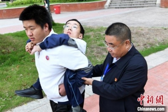 朱金祥背著鐘華強去教室上課的路上，也經常碰到值班的校領導和老師前來搭把手。 卓忠偉 攝