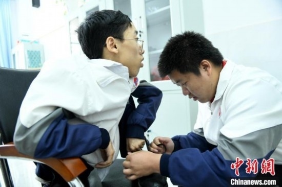 江西省南康中學北校區(qū)的高三學生朱金祥(右)正在給鐘華強(左)系好鞋帶。 卓忠偉 攝