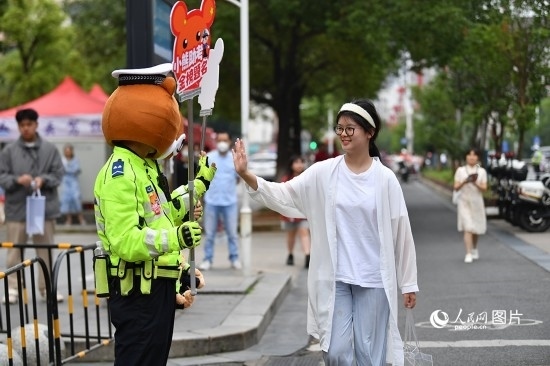 6月7日上午9時(shí)，隨著鈴聲的響起，2023年江西高考正式開考，江西省的53.57萬考生以縣（區(qū)）為單位隨機(jī)安排在全省256個(gè)考點(diǎn)、18968個(gè)考場參加高考。圖為“小熊交警”和考生擊掌鼓勵(lì)。 人民網(wǎng)記者 時(shí)雨攝