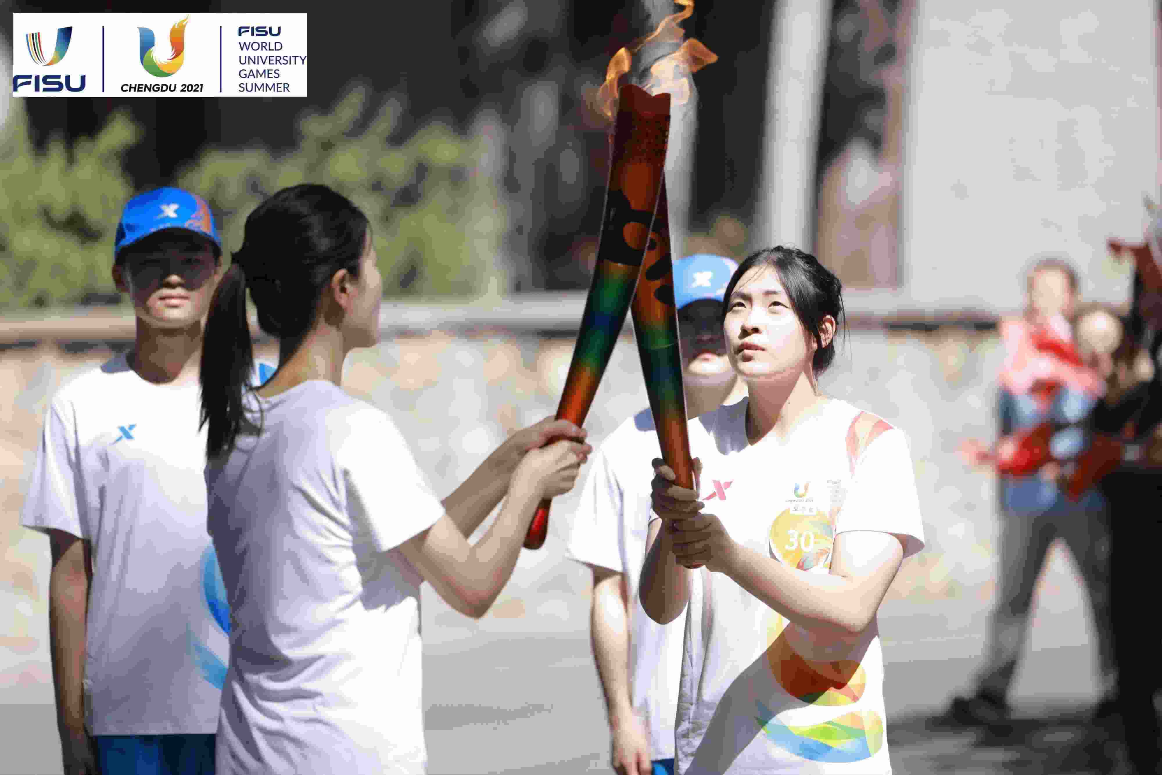 兩名大運(yùn)會火炬手進(jìn)行火炬?zhèn)鬟f。 圖片來源：成都大運(yùn)會執(zhí)委會供圖