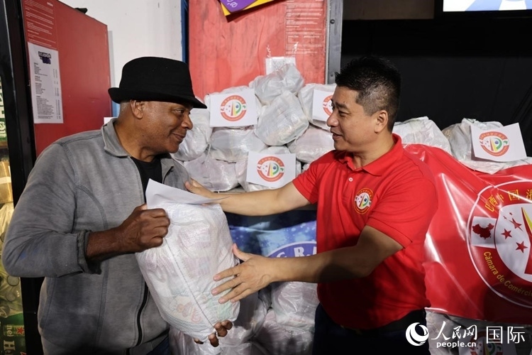 巴西中國(guó)浙江商會(huì)會(huì)長(zhǎng)鄭俠茂向社區(qū)居民轉(zhuǎn)交捐贈(zèng)物資。人民網(wǎng)記者 時(shí)元皓攝
