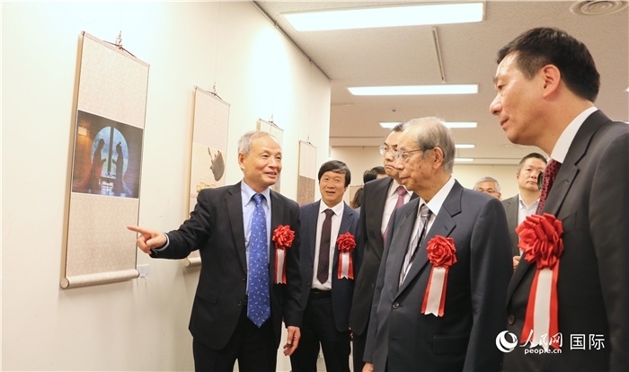 “湖州印象”攝影展主創(chuàng)、世界華人攝影協(xié)會副會長馮學敏向吳江浩大使、福田康夫前首相等嘉賓介紹展出作品。（人民網(wǎng) 許可攝）