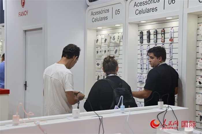 幾名參觀者在一個展臺前了解手機配件。（人民網(wǎng)記者 時元皓攝）