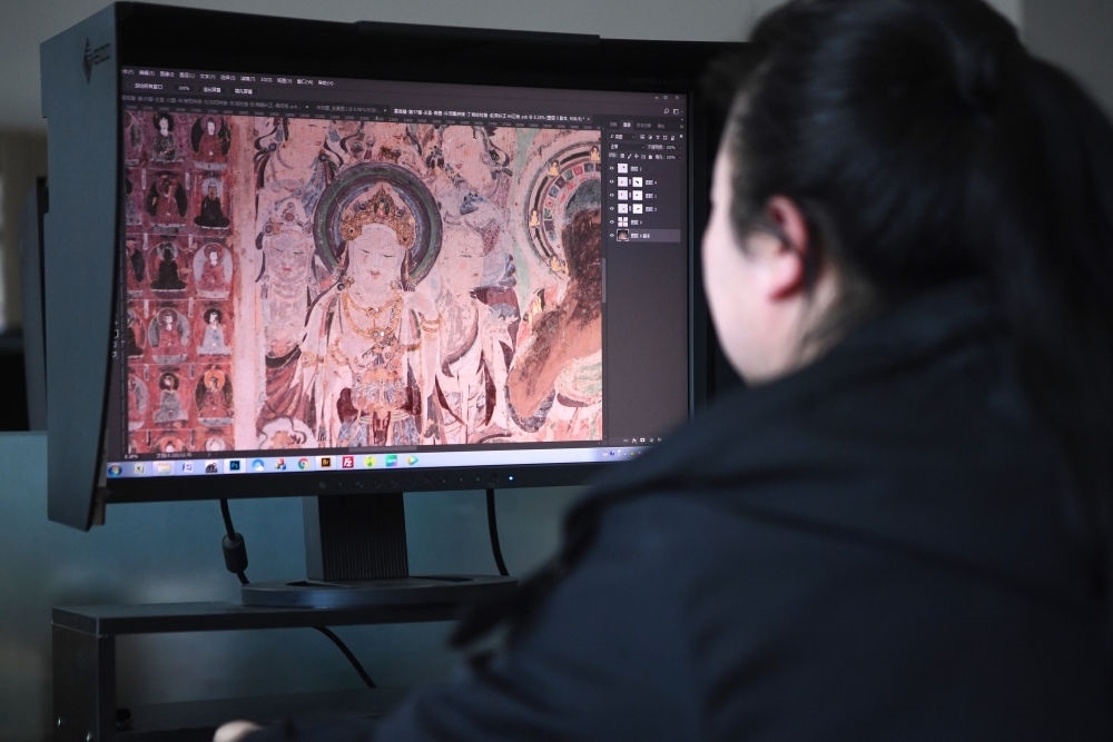 敦煌研究院文物數(shù)字化保護(hù)團(tuán)隊(duì)圖像處理人員年海麗在拼接壁畫圖像（2023年4月25日攝）。數(shù)字化探索為莫高窟的保護(hù)與傳承開辟了全新路徑，數(shù)字技術(shù)讓敦煌文物走出洞窟，跨出國(guó)門，走向“永久保存、永續(xù)利用”。新華社記者 陳斌 攝