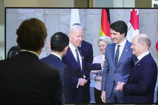 2022年3月24日，在比利時(shí)布魯塞爾的北約總部，一名男子觀看屏幕上美國總統(tǒng)拜登（右四）、歐盟委員會主席馮德萊恩（右三）、加拿大總理特魯多（右二）、德國總理朔爾茨（右一）出席七國集團(tuán)峰會合影儀式的畫面。新華社記者鄭煥松攝