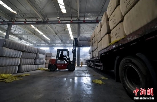 新疆喀什綜合保稅區(qū)，喀什啟路國(guó)際貿(mào)易有限公司的倉(cāng)庫(kù)內(nèi)，工人正在裝載從塔吉克斯坦和烏茲別克斯坦進(jìn)口的棉花。劉新攝