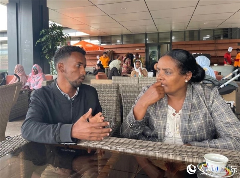 約漢斯（圖左）與德貝拉在友誼廣場咖啡廳交談。人民網記者 趙艷紅攝