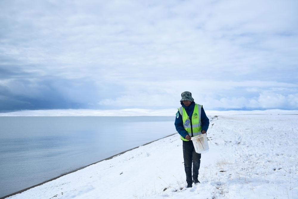 2021年10月20日，在青海省果洛藏族自治州瑪多縣扎陵湖鄉(xiāng)勒那村，三江源國家公園黃河源園區(qū)生態(tài)管護員在扎陵湖邊撿拾垃圾。新華社記者 張龍 攝