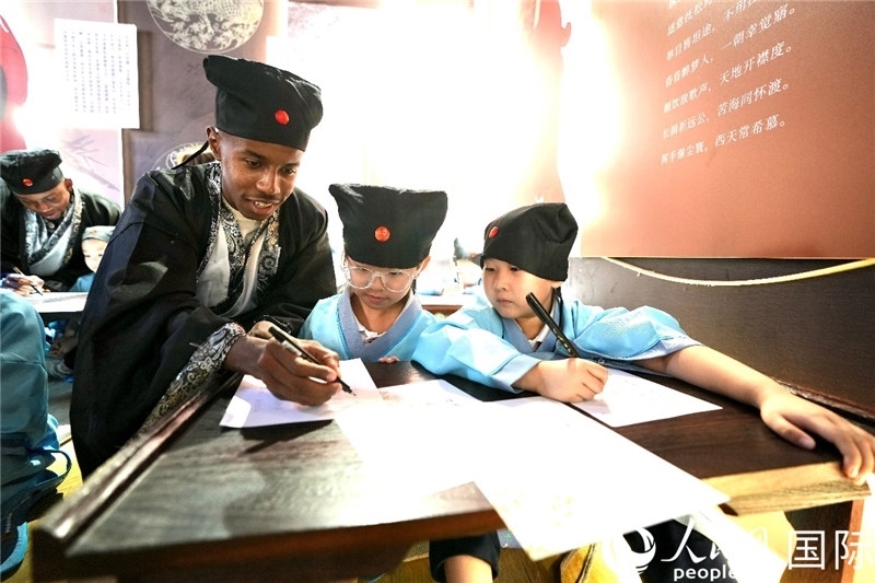 圖為選手與同學們一起寫書法。人民網(wǎng) 盧鵬宇攝