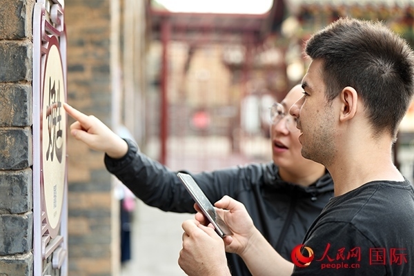 選手安德烈（俄羅斯）在老師指導(dǎo)下學(xué)習(xí)墻壁上張貼的生僻字。人民網(wǎng) 盧鵬宇攝