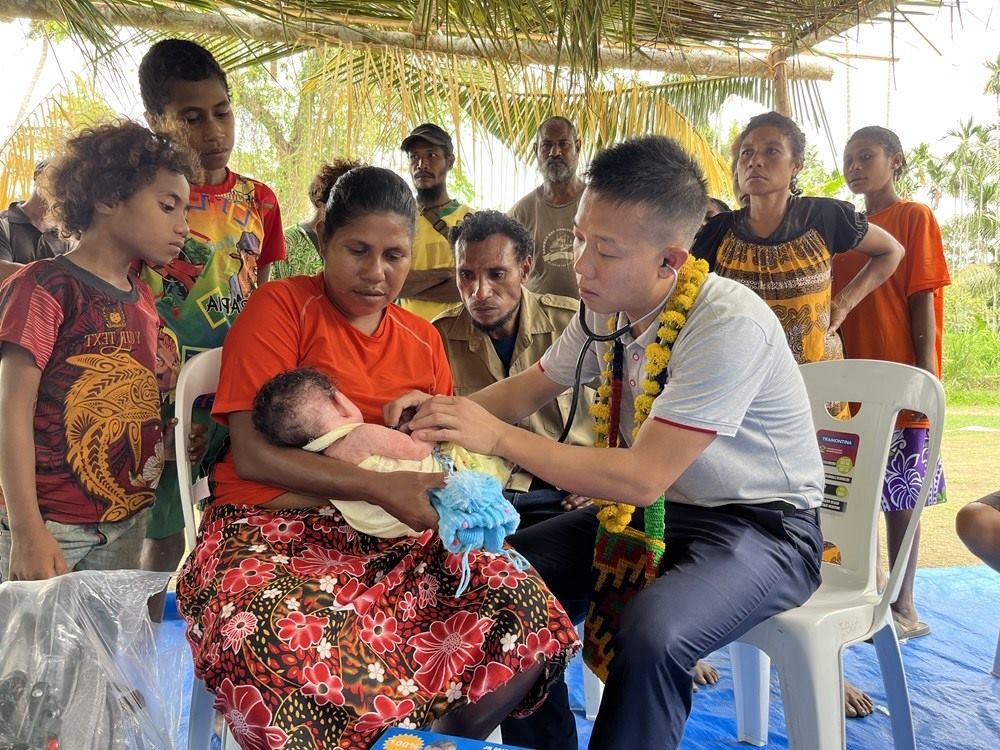 2023年8月5日，在巴布亞新幾內(nèi)亞中央省的一個(gè)村莊里，第12批援巴新中國(guó)醫(yī)療隊(duì)副隊(duì)長(zhǎng)、新生兒科副主任醫(yī)師劉振球?yàn)楫?dāng)?shù)貗雰郝?tīng)診檢查。新華社發(fā)（第12批援巴新中國(guó)醫(yī)療隊(duì)供圖）