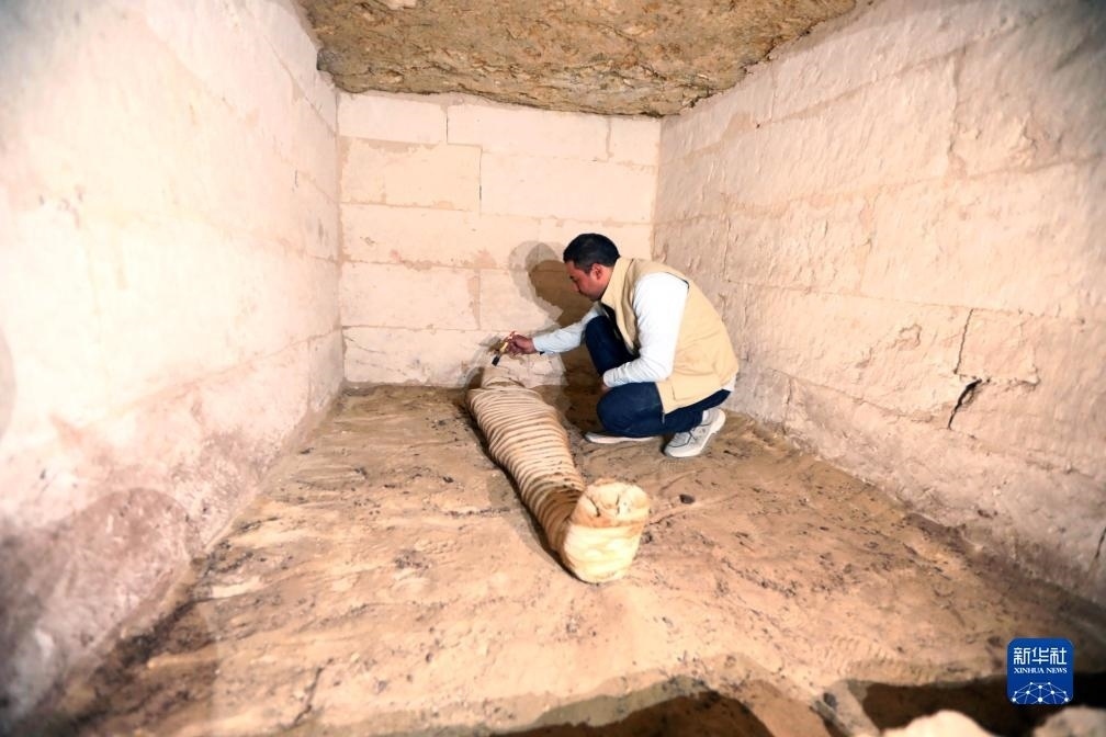 10月15日，在埃及明亞省考古現(xiàn)場，考古人員清理一座石鑿墓中的木乃伊。新華社發(fā)（艾哈邁德·戈馬攝）