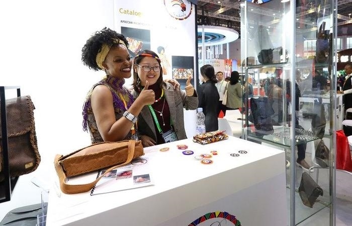 11月6日，一位參觀者（右）在第六屆進(jìn)博會(huì)國(guó)家展南非展臺(tái)試戴傳統(tǒng)首飾。