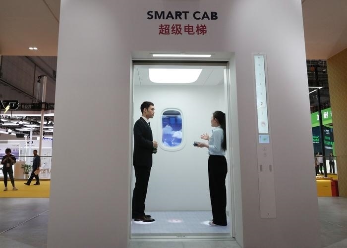 11月5日，工作人員（右）在第六屆進(jìn)博會(huì)上向參觀者介紹奧的斯公司全新推出的超級(jí)電梯。