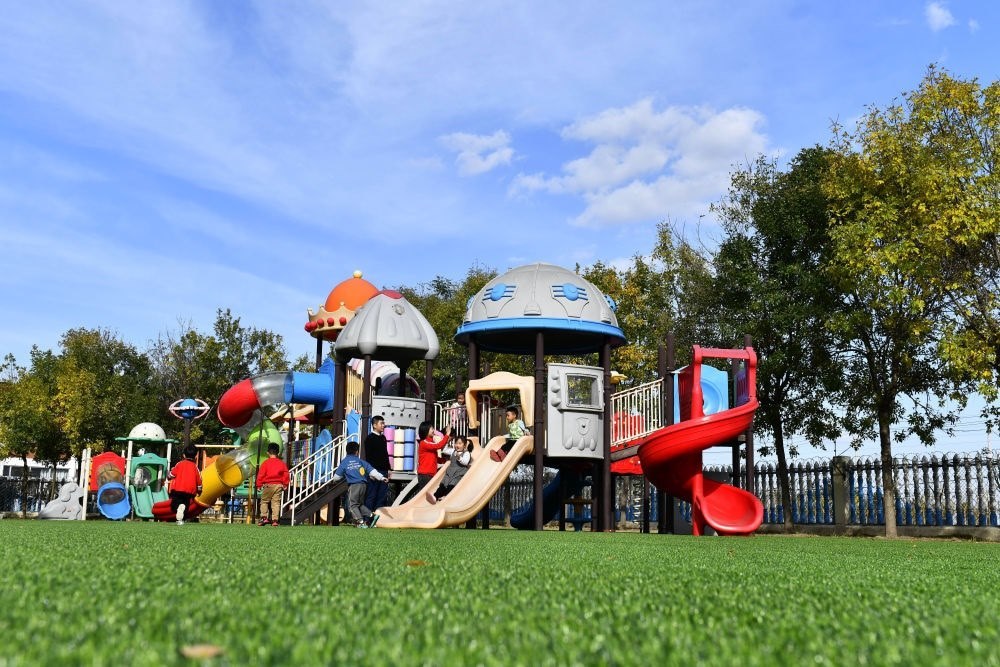 在山東省東營市墾利區(qū)楊廟社區(qū)幼兒園，孩子們?cè)诶蠋煹膸ьI(lǐng)下進(jìn)行戶外活動(dòng)（2021年10月19日攝）。新華社記者 郭緒雷 攝