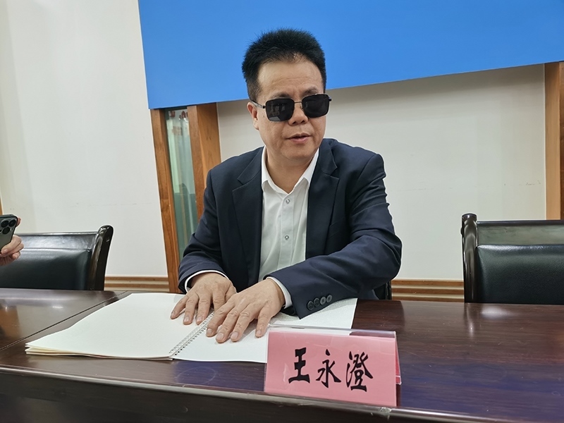 全國(guó)人大代表王永澄正在閱讀盲文版代表建議答復(fù)。本報(bào)記者 張 璁?dāng)z