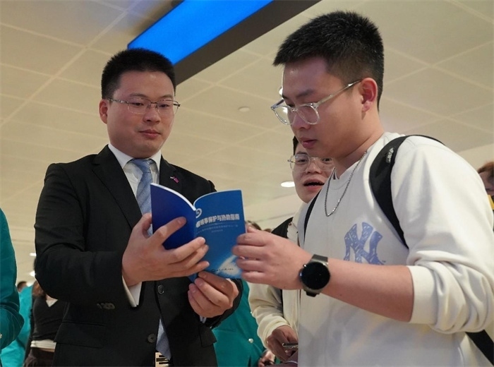 工作人員（左一）在發(fā)放《中國(guó)領(lǐng)事保護(hù)與協(xié)助指南》。 中國(guó)駐迪拜總領(lǐng)事館供圖