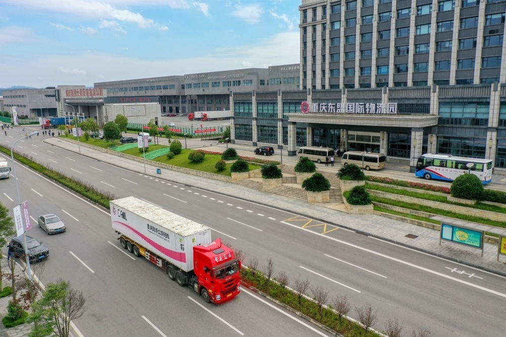 2023年10月11日，滿(mǎn)載筆記本電腦配件、發(fā)電機(jī)組件等產(chǎn)品的西部陸海新通道跨境公路班車(chē)從重慶南彭公路保稅物流中心駛出，將途經(jīng)廣西憑祥，直達(dá)越南（無(wú)人機(jī)照片）。新華社記者 黃偉 攝