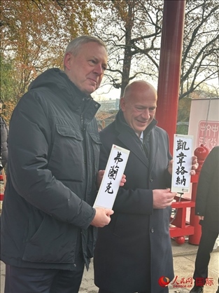 柏林市長韋格納（右）、動物園監(jiān)事會主席布魯克曼（左）手持中國文化中心工作人員現(xiàn)場手書的中文名字。人民網(wǎng)記者 徐馨攝