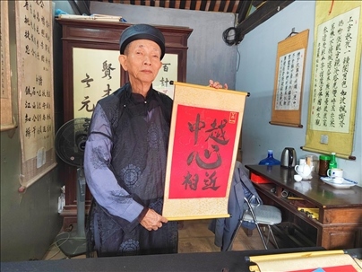越南首都河內(nèi)文廟內(nèi)，阮明珠展示“中越心相近”書法作品。