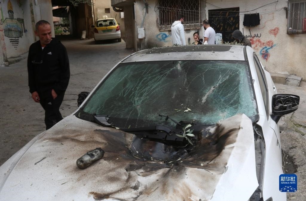 12月17日，在約旦河西岸城市圖勒凱爾姆附近的一處難民營，人們查看在沖突中損毀的車輛。新華社發(fā)（尼達(dá)爾·艾仕塔耶?dāng)z）