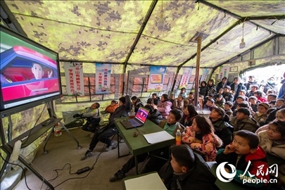 12月22日，在積石山縣大河家鎮(zhèn)大河村安置點(diǎn)，陸軍76集團(tuán)軍某旅搭建的“臨時(shí)學(xué)?！眱?nèi)，小朋友正在看動(dòng)畫片。人民網(wǎng)記者 翁奇羽攝