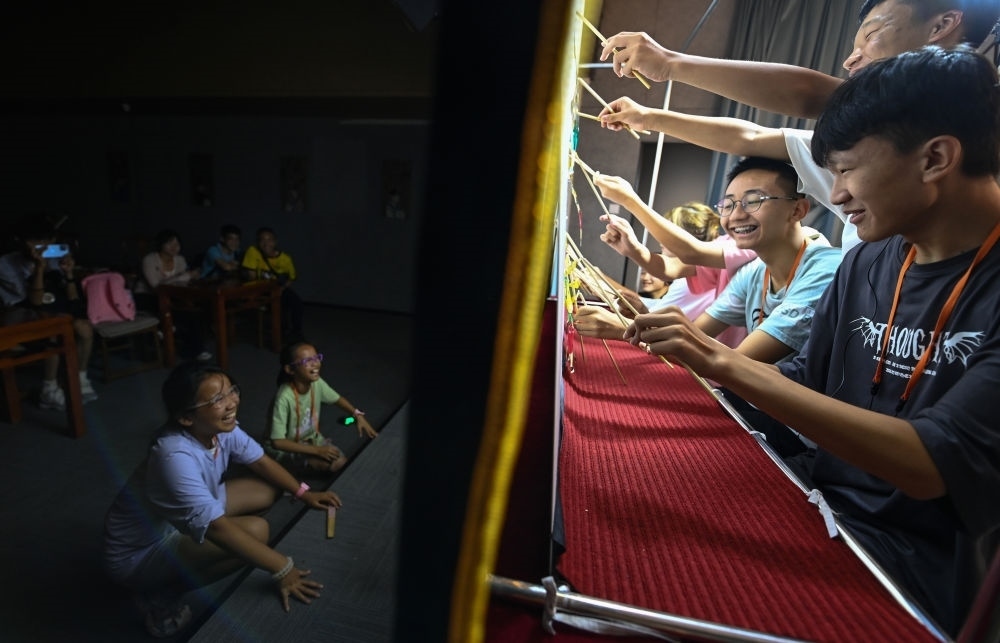 2023年8月8日，進(jìn)行暑期研學(xué)的學(xué)生在位于陜西省西安市的中國秦腔藝術(shù)博物館體驗皮影戲演出。新華社記者 鄒競一 攝