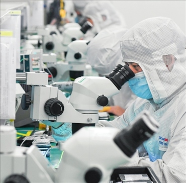 在位于武漢中國光谷的光電器件研發(fā)制造商——武漢光迅科技股份有限公司生產(chǎn)車間內(nèi)，技術(shù)人員在光模塊生產(chǎn)線作業(yè)（2023年4月11日攝）。程敏攝/本刊