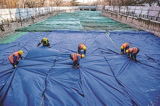 1月3日，房山區(qū)東風(fēng)街道，工人正在修復(fù)的河道內(nèi)給混凝土鋪設(shè)保溫布。