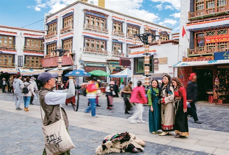 千年八廓街，見證民族團結。2021年7月，習近平總書記來到位于西藏拉薩老城區(qū)的八廓街，感慨地說：“千年八廓街，是我們各民族建起來的八廓街。各民族文化在這里交流交往交融，我們中華民族的大家庭在這里其樂融融。”圖為2023年6月13日，游客身著藏裝在八廓街拍照留念。 新華社記者 姜帆/攝