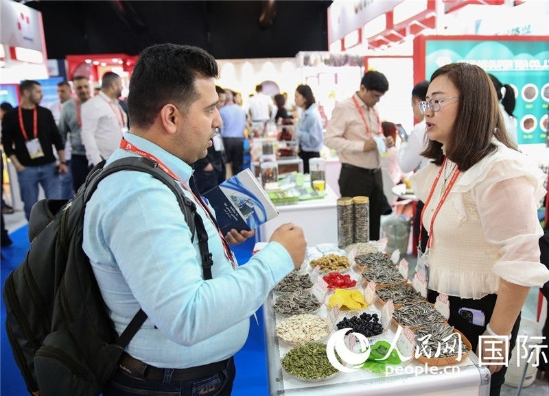 圖為一家中國干果參展企業(yè)代表與采購商洽談。人民網(wǎng) 塔里克·易卜拉欣攝