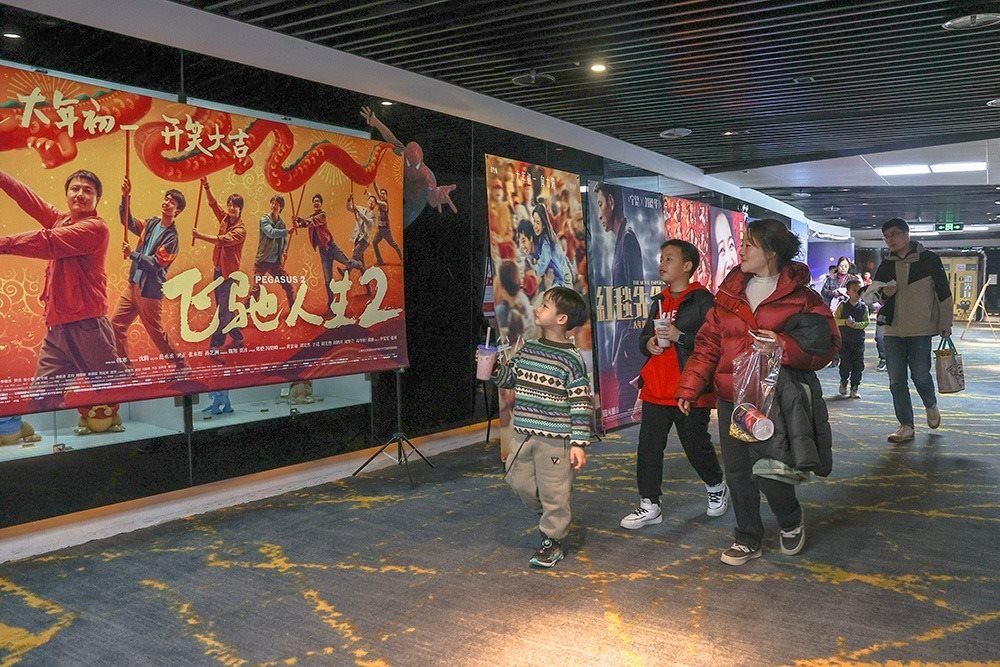 △ 2024年2月16日，在江西贛州一家電影院，觀眾從春節(jié)檔電影的宣傳展板前走過(guò)。
