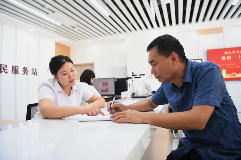 2023年5月23日，河北雄安新區(qū)容東片區(qū)南文營(yíng)社區(qū)居民（右）在社區(qū)便民服務(wù)站辦理業(yè)務(wù)。