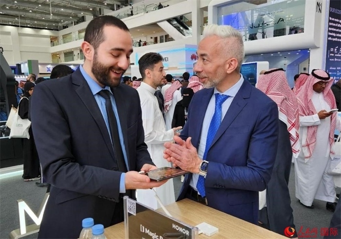 兩名觀眾在榮耀手機展臺前交流。人民網(wǎng)記者 管克江攝