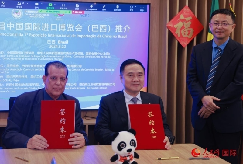 巴西外貿(mào)商會聯(lián)合會會長阿代爾·羅伯托（左）與中國國際進(jìn)口博覽局副局長吳政平（中）現(xiàn)場簽訂協(xié)議。人民網(wǎng)記者 宋亦然攝