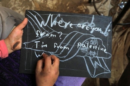 2023年12月28日，一名學(xué)生在加沙地帶南部城市拉法一所學(xué)校的臨時(shí)教室中寫(xiě)下“我來(lái)自巴勒斯坦”的字樣。新華社發(fā)（里澤克·阿卜杜勒賈瓦德攝）