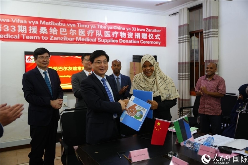 江蘇省蘇北人民醫(yī)院黨委書記束余聲與桑衛(wèi)生部首席秘書哈比巴交換捐贈(zèng)書。中國(guó)援桑醫(yī)療隊(duì)供圖