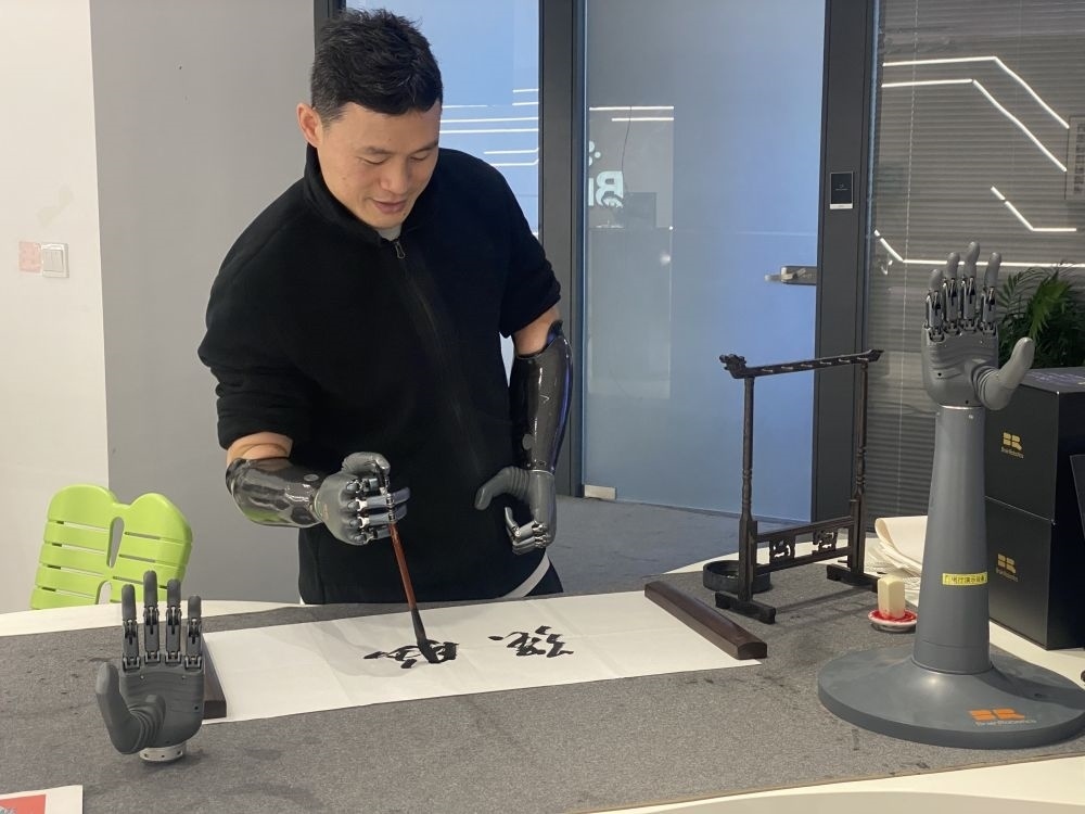 2024年3月29日，在浙江強腦科技有限公司展廳內，失去雙手的產品體驗官倪敏成依靠智能仿生手寫毛筆字。新華社記者 魏一駿 攝