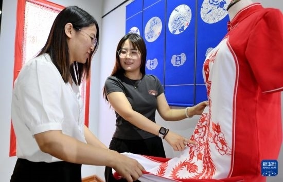 5月31日，在衡水市阜城縣一家剪紙工作室，游客在觀賞帶有剪紙?jiān)氐钠炫邸? width=