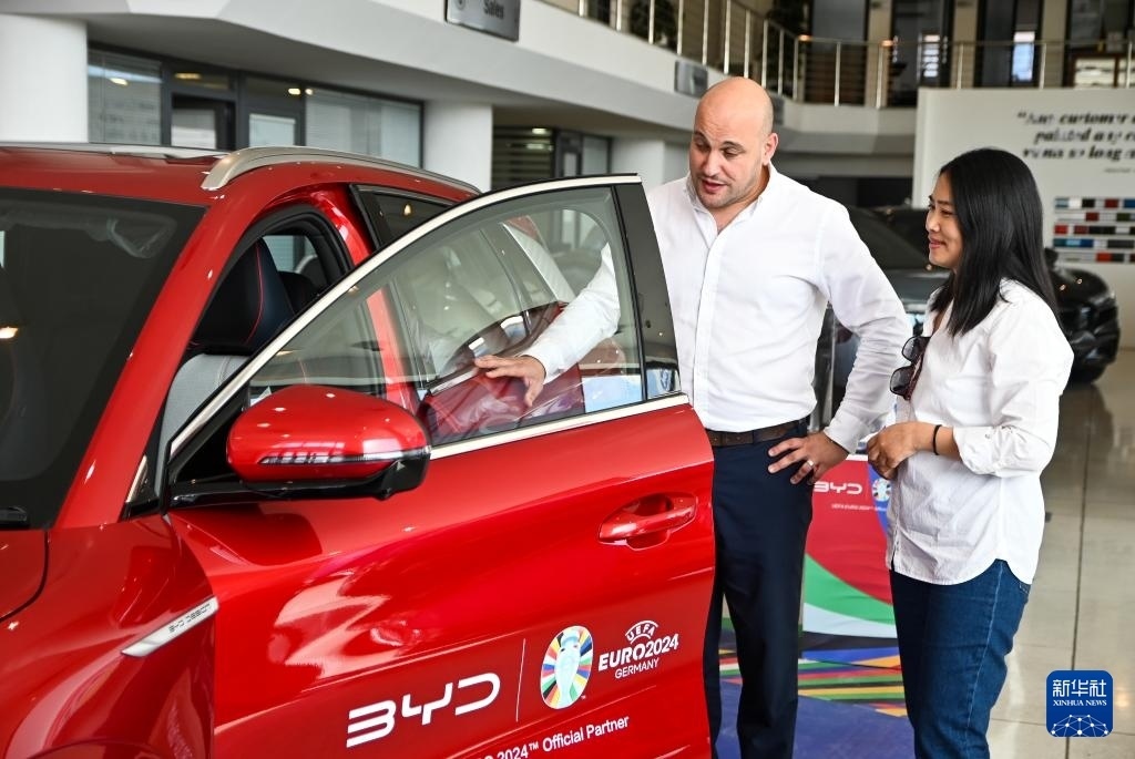 2024年5月29日，在馬耳他比爾基卡拉，馬耳他哈桑-扎米特汽車(chē)公司首席執(zhí)行官德古阿拉（左）介紹一輛比亞迪純電動(dòng)汽車(chē)。新華社發(fā)（喬納森·博格 攝）