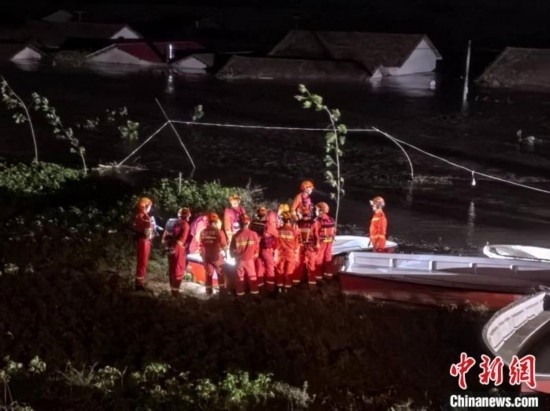  7月6日凌晨3時(shí)，在湖南岳陽(yáng)華容縣團(tuán)洲垸洞庭湖一線堤防，救援人員剛剛完成一次救援任務(wù)，遠(yuǎn)處是被淹的民房。中新社記者 白祖偕 攝