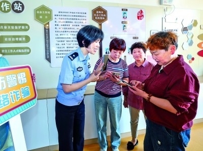 浙江湖州民警指導(dǎo)居民加入湖州“e企安”微信群，實時接收反詐信息。新華社發(fā)