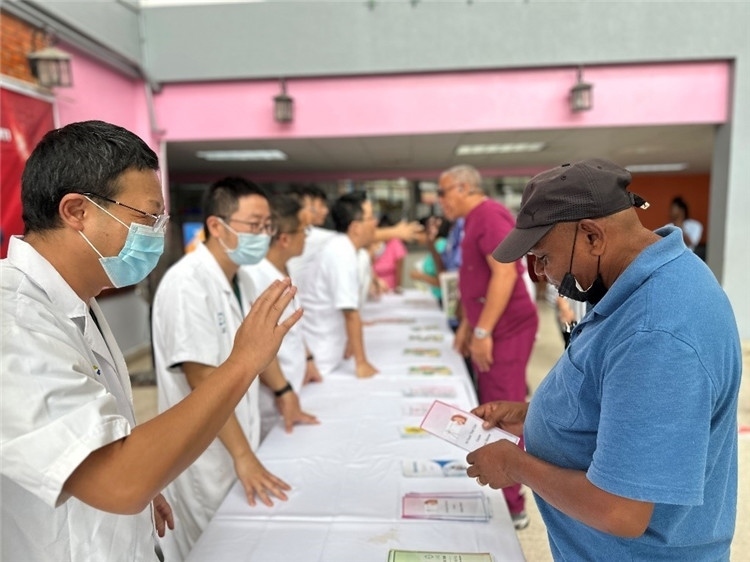 援圭醫(yī)療隊(duì)隊(duì)員們?cè)趩?dòng)儀式上為當(dāng)?shù)孛癖姺职l(fā)宣傳手冊(cè)。中國援助圭亞那醫(yī)療隊(duì)供圖