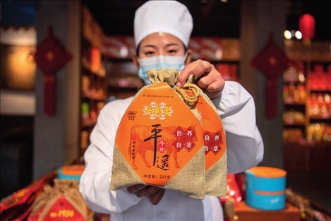 在位于山西省晉中市平遙縣的平遙古城南大街的一家平遙牛肉店內，工作人員展示一款牛肉產(chǎn)品（資料照片）楊晨光攝 / 本刊