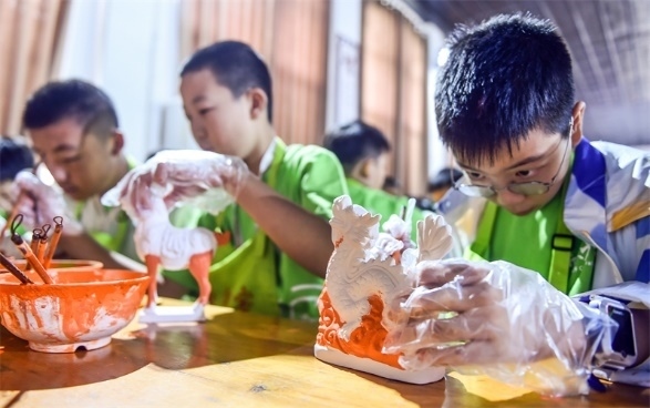 小朋友們在洛陽市孟津區(qū)朝陽鎮(zhèn)南石山村體驗唐三彩素胎施釉技藝。圖片來源：視覺中國