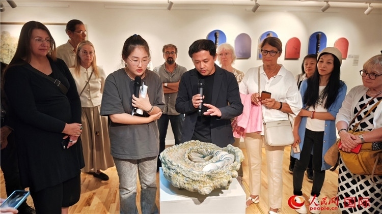 參展人、景德鎮(zhèn)陶瓷大學(xué)設(shè)計(jì)藝術(shù)學(xué)院副院長余劍峰（中）向來賓介紹參展作品。人民網(wǎng)記者 殷淼攝