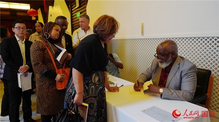 譚哲理在活動現(xiàn)場簽名贈書。人民網(wǎng) 劉暢攝