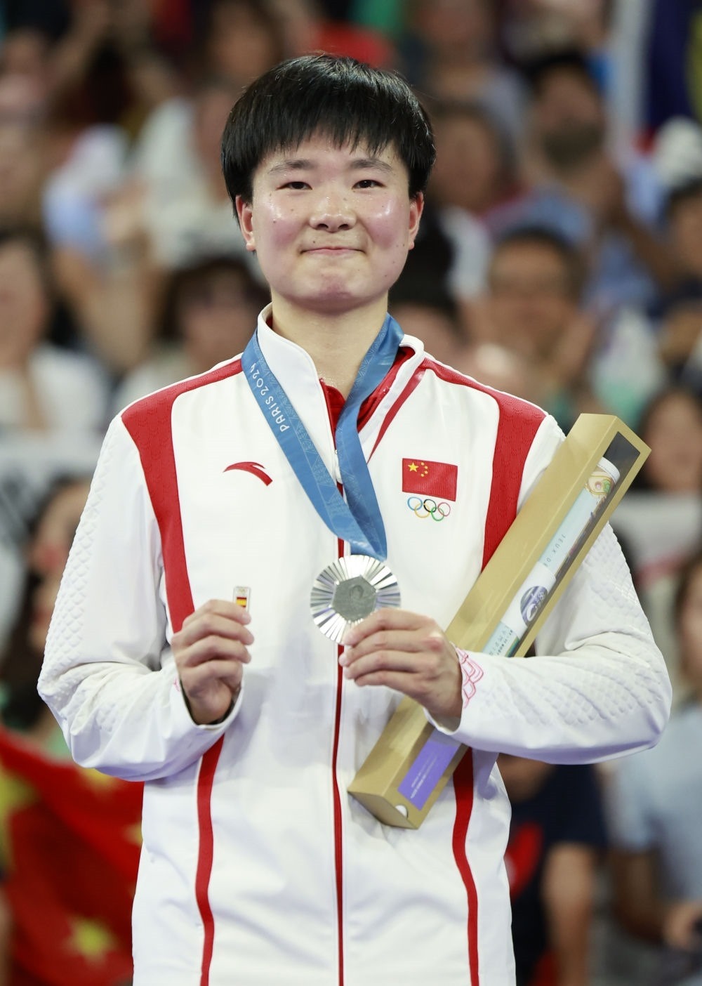 巴黎奧運會羽毛球女子單打亞軍、中國選手何冰嬌在頒獎儀式上一手握著銀牌，一手握著西班牙奧委會徽章（2024年8月5日攝）。新華社記者 任正來 攝